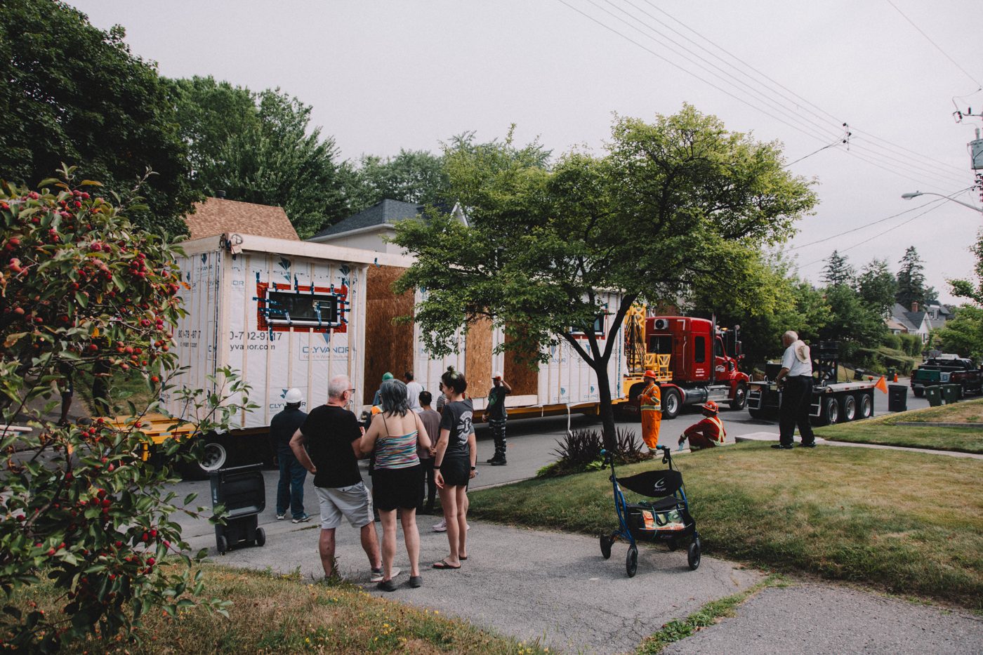Neighbours watching a factory-built module arrive on a North York street